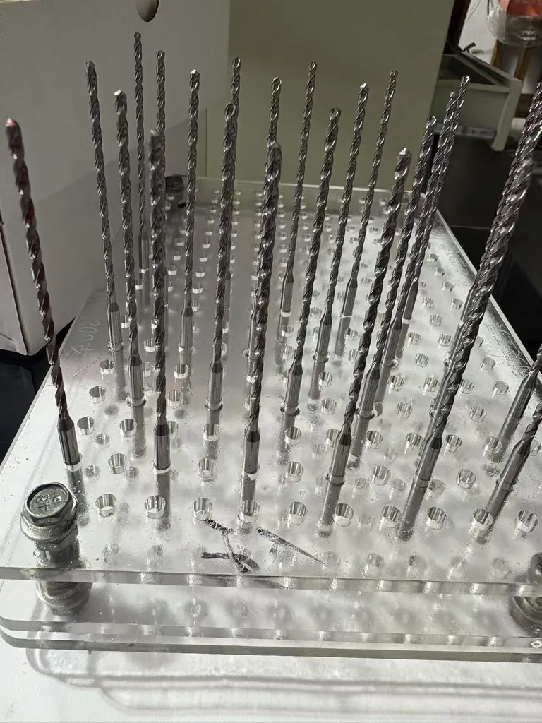 Workshop photograph of micro-diameter deep coolant-through solid carbide drills before coating, showing long flute length relative to diameter